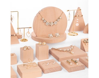 Puede incluir: Un conjunto de expositores de joyería de madera en varias formas y tamaños. Los expositores están hechos de madera natural y presentan un color marrón claro. Los expositores son perfectos para exhibir collares, aretes, anillos y pulseras.
