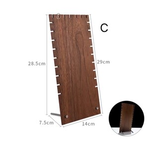 Puede incluir: Expositor de joyas de madera con acabado en madera marr&oacute;n y base de metal. El expositor tiene 14 ranuras para collares o pulseras. El expositor mide 28,5 cm de alto, 7,5 cm de ancho y 14 cm de largo. El expositor est&aacute; etiquetado con "C".