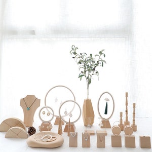 Könnte beinhalten: Ein Satz aus Holz-Schmuckständern in verschiedenen Formen und Größen. Die Ständer sind aus Naturholz gefertigt und verfügen über eine Vielzahl von Designs, darunter Kreise, Ovale und Rechtecke. Die Ständer sind perfekt zum Präsentieren von Halsketten, Ohrringen, Armbändern und Ringen.