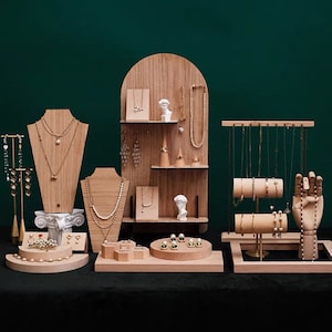 May include: Wooden jewelry display stand with multiple tiers and compartments for necklaces, earrings, bracelets, and rings. The stand features a bust, a hand, and a cone-shaped display.