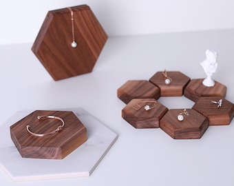 May include: A set of hexagonal wooden display stands for jewelry. The stands are made of dark wood and come in different sizes. The stands are perfect for displaying necklaces, bracelets, earrings, and rings.