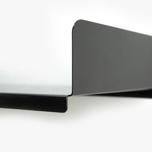 May include: A black metal shelf with a curved edge. The shelf is mounted to a white wall.