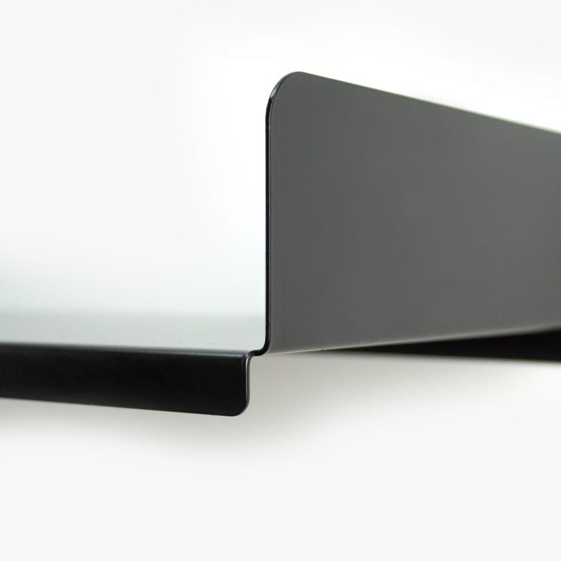 May include: A black metal shelf with a curved edge. The shelf is mounted to a white wall.