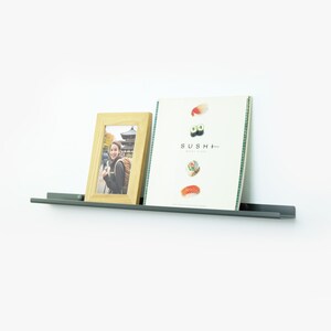 May include: A gray metal shelf with a wooden picture frame and a magazine titled "SUSHI+" on it. The picture frame contains a photo of a person in front of a Japanese temple.