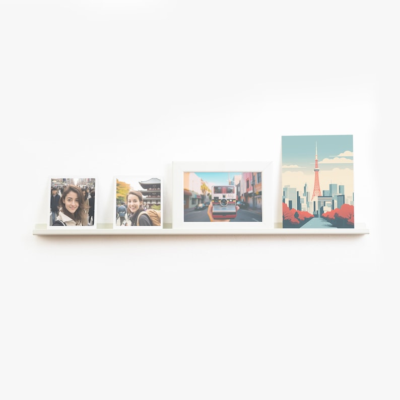May include: Three white picture frames with photos of a woman in Japan, a woman taking a photo of a street scene, and a cityscape with a tower. The frames are on a white shelf against a white wall.