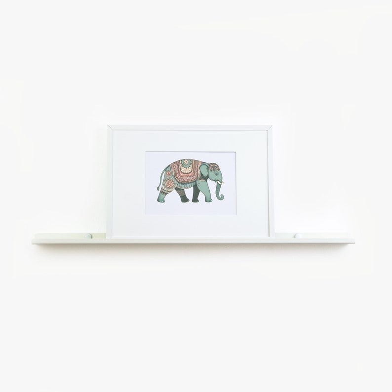 May include: A white framed print of a teal elephant with colorful patterned decorations on its back. The elephant is walking to the right. The print is on a white shelf.