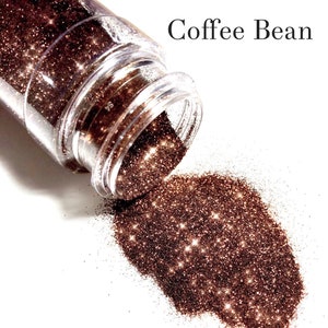 May include: A clear jar with a brown glitter inside, spilling out onto a white surface. The glitter is labeled "Coffee Bean".