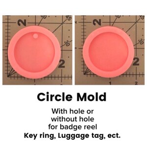 May include: Two pink silicone circle molds for crafting. The molds are 2 inches in diameter and have a small hole in the center. The molds are on a grid background.