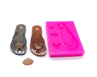 Op de afbeelding: Twee glitterende flip-flop charms, een gouden en een zwarte, met een roze siliconen mal met een flip-flop, schelp en ster ontwerp.