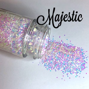 May include: A clear jar with a white, iridescent, and pink glitter mix spilling out onto a white surface. The jar is labeled "Majestic".
