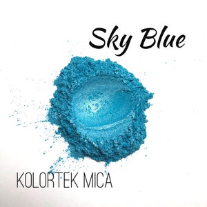 May include: A close-up of a pile of sky blue mica powder. The powder is a fine, shimmery powder that is perfect for adding a touch of sparkle to any project. The powder is labeled "Kolorek Mica".