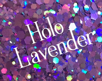 Op de afbeelding: Close-up van iriserende paarse glitter met een holografisch effect. De glitterstukjes zijn zeshoekig en reflecteren verschillende kleuren. De tekst "Holo Lavender" wordt in het wit over de afbeelding weergegeven.