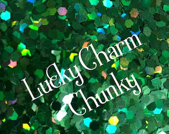 Könnte beinhalten: Grün schimmernder, grober Glitter mit dem Text "Lucky Charm" darauf.