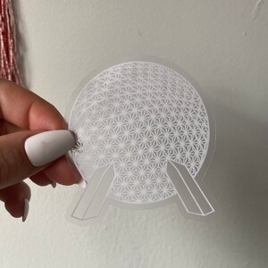 以下が含まれることがあります： エプコットのスペースシップアースアトラクションの輪郭を詳細に描いた、透明な背景を持つ白いビニールステッカーです。
