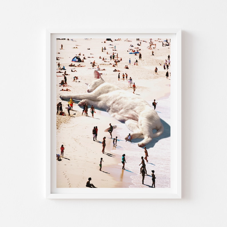 May include: A white cat, much larger than humans, is lying on a beach. People are walking around the cat, some are even standing on its back. The cat is sleeping peacefully.