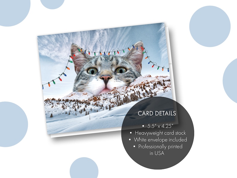 May include: A Christmas card featuring a cat's face peeking over a snowy mountain range with Christmas lights strung across the top. The card details are listed below: 5.5" x 4.25", Heavyweight card stock, White envelope included, Professionally printed in USA.