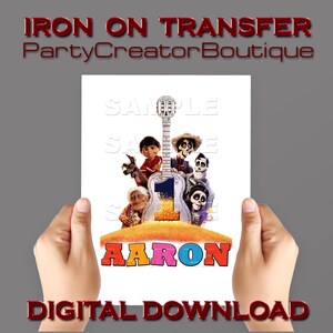 May include: Iron-on transfer featuring characters from the animated film Coco. The transfer includes a guitar, a skeleton, and a colourful background. The name "AARON" is written in large, colourful letters at the bottom of the transfer.