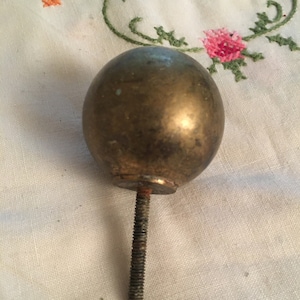 Può includere: Un terminale in metallo dorato con una parte superiore rotonda e uno stelo filettato. Il terminale ha un diametro di circa 5 cm.