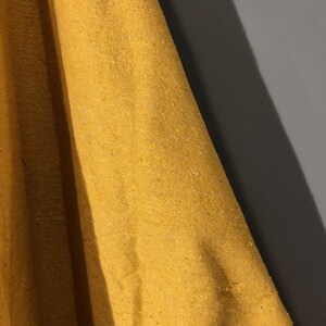 May include: Close-up of a mustard yellow fabric with a textured weave.