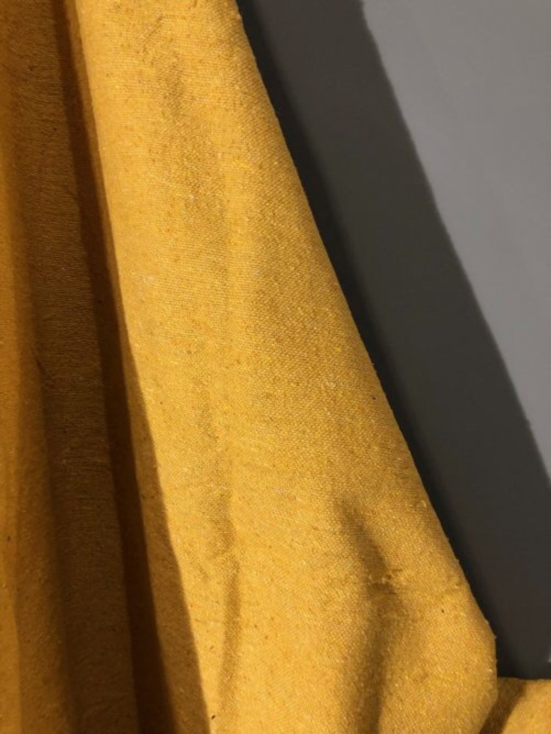 May include: Close-up of a mustard yellow fabric with a textured weave.