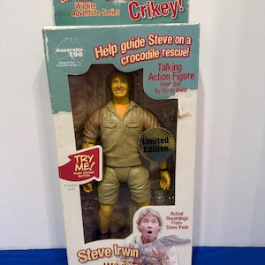 Könnte beinhalten: Eine Steve Irwin Wildlife Adventure Series Actionfigur in Originalverpackung. Die Figur trägt ein khaki Hemd und Shorts. Die Box zeigt den Text "Crikey!" und "Help guide Steve on a crocodile rescue!" und "Limited Edition".