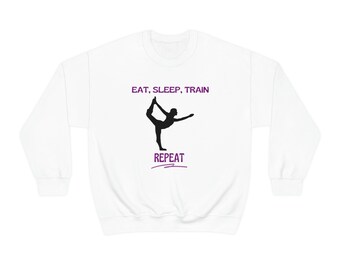 May include: White sweatshirt with a black silhouette of a person in a yoga pose. The text "EAT, SLEEP, TRAIN, REPEAT" is printed in purple on the sweatshirt.