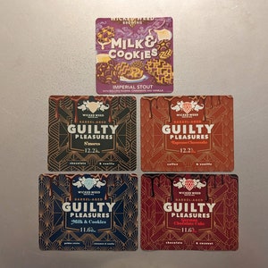 May include: Four different beer bottle labels with a dark red, black, blue, and orange background. The labels feature a stylized design with the text "Wicked Weed Brewing" and "Guilty Pleasures" in gold lettering. The labels also include the names of the beers: "S'mores", "Espresso Chocolate", "Milk & Cookies", and "German Chocolate Cake".