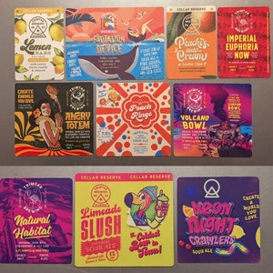 May include: A collection of 10 colorful square stickers featuring different sour ale beers from Trimtab Brewing. The stickers feature various illustrations and text, including "Lemon Bars", "Flotation Device", "Peaches and Cream", "Imperial Euphoria Now", "Create a World You Love", "Angry Totem", "Peach Ringo", "Volcano Bowl", "Natural Habitat", "Limeade Slush", "Neon Night Crawlers", and "The Coldest Beer in Town!"