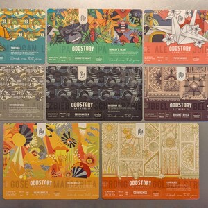 May include: Nine rectangular cards with colorful illustrations and text. Each card features the "ODDSTORY" logo and various designs, including a turtle, gorilla, and origami. The cards are arranged on a gray surface.