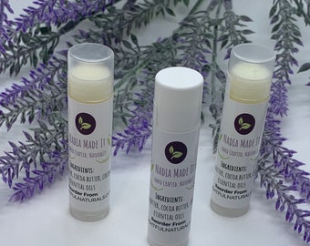 May include: Three white tubes of lip balm with a green leaf logo and the text "Nadia Made It Hand Crafted, Naturally" and "Ingredients: Shea Butter, Cocoa Butter, Coconut Oil, Essential Oils Reorder From:  SHTFULNATURALS"