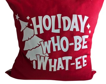Puede incluir: Un cojín decorativo rojo con texto blanco "HOLIDAY WHO-BE WHAT-EE" y un diseño de árbol de Navidad blanco. El cojín es cuadrado y está hecho de tela texturizada.