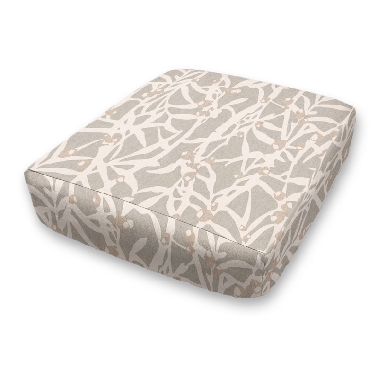 May include: A square, beige cushion with a light brown floral pattern. The cushion is made of a soft, textured fabric.