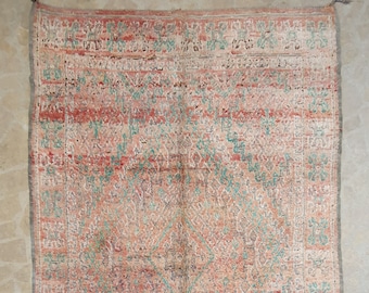 May include: A vintage rug with a geometric pattern in shades of red, pink, blue, and white. The rug has a distressed look and is made of wool.