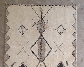 May include: A white rug with a geometric pattern in black and gray. The rug has a fringe border.