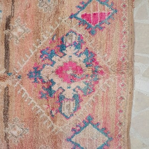 May include: A vintage Moroccan rug with a beige background and intricate patterns in shades of pink, blue, and white.
