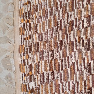 May include: A brown, white, and orange patterned rug with fringe on the edges.