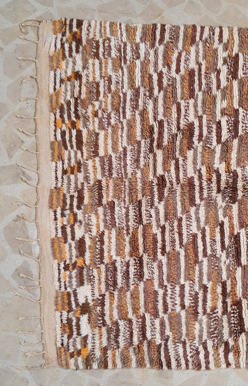 May include: A brown, white, and orange patterned rug with fringe on the edges.