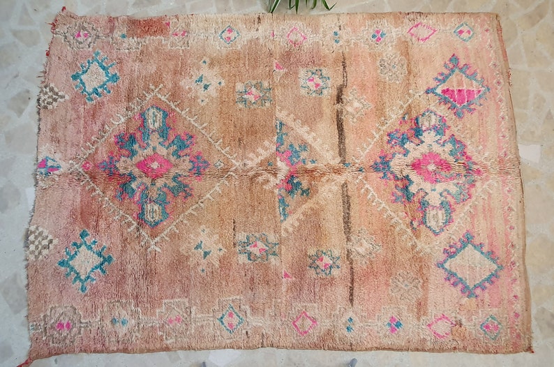 May include: A vintage Moroccan rug with a beige background and intricate geometric patterns in shades of pink, blue, and white.