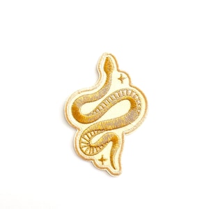 May include: A gold embroidered snake patch with a white background and two gold stars.