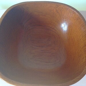 May include: A large, square wooden bowl with a smooth, dark brown finish. The bowl is empty and ready to be used.
