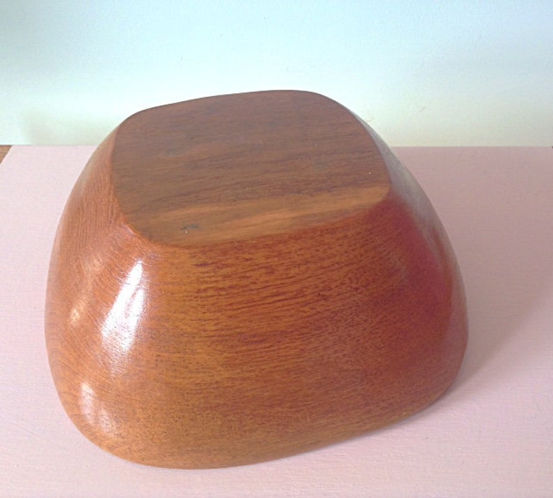 May include: A large, wooden bowl with a smooth, rounded shape. The bowl is made of light brown wood and has a natural, polished finish.