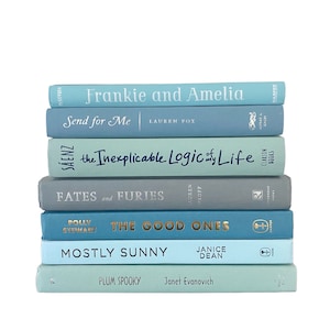 May include: A stack of eight blue and green hardcover books with various titles, including "Frankie and Amelia", "Send for Me", "The Inexplicable Logic of My Life", "Fates and Furies", "The Good Ones", "Mostly Sunny", and "Plum Spooky".