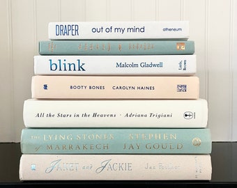 May include: A stack of books with light blue and cream colored covers. The titles include "blink", "Booty Bones", "All the Stars in the Heavens", "The Lying Stones", and "Janet and Jackie".