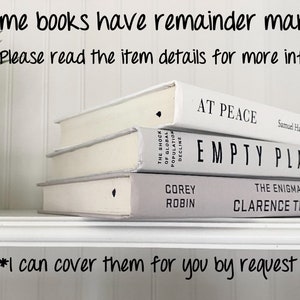 May include: Three white hardcover books stacked on a shelf. The top book is titled "At Peace" by Samuel Harrington, MD. The middle book is titled "Empty Plane". The bottom book is titled "The Enigma of" by Corey Robin and Clarence Thomas.