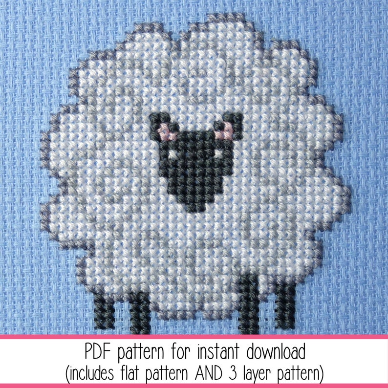 Close up of a simple cross stitch of a small stylised sheep stitched on blue Aida. The listing is for the PDF cross stitch pattern.