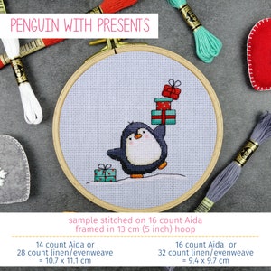 May include: A cross-stitch pattern of a penguin holding a stack of presents. The pattern is stitched on 16 count Aida fabric and framed in a 5 inch hoop. The text "PENGUIN WITH PRESENTS" is at the top of the image. The image also includes floss in various colors.