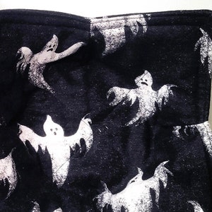 May include: Two black fabric coasters with a white ghost pattern. The coasters are square and have a quilted texture.