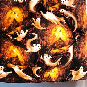 May include: Two brown and orange fabric pot holders with a pattern of white ghosts in a dark forest setting.