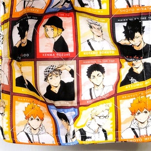 May include: Two white fabric bowl cozies with a colorful anime print featuring characters from the show "Haikyuu!!". The cozies are quilted and have a black border.