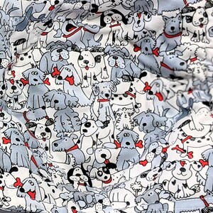 May include: Two gray and white fabric bowl cozies with a pattern of cartoon dogs. The cozies are lined with a white fabric and have a red trim.